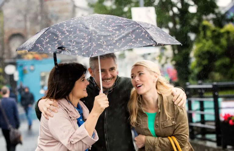 Three people wearing hearing aids under an umbrella.