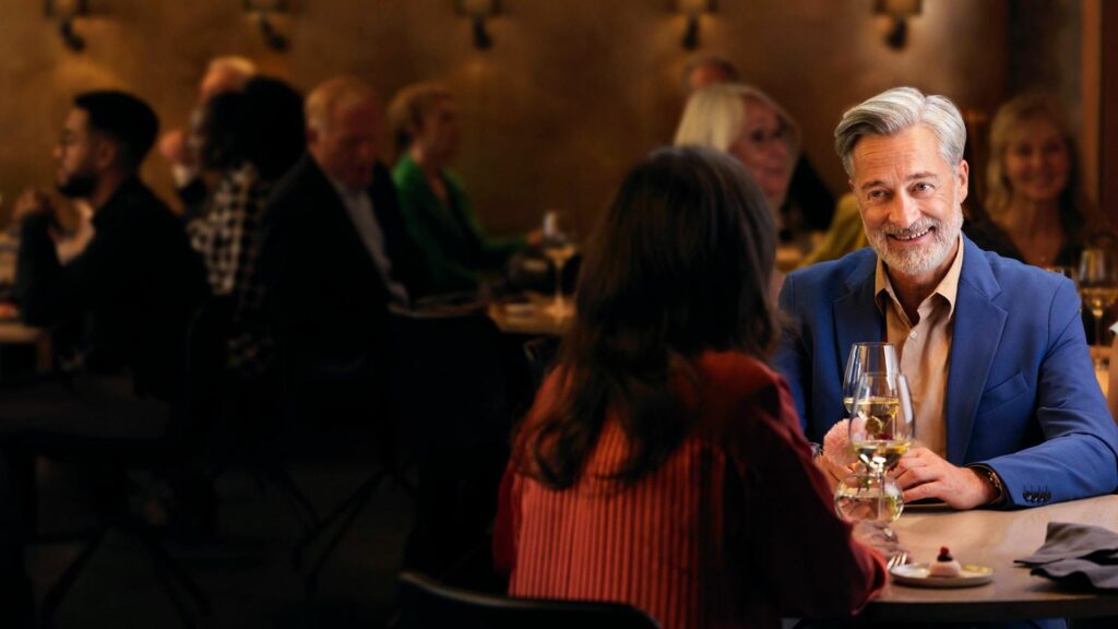 Man wearing ReSound Omnia Mini hearing aids in a dining setting.